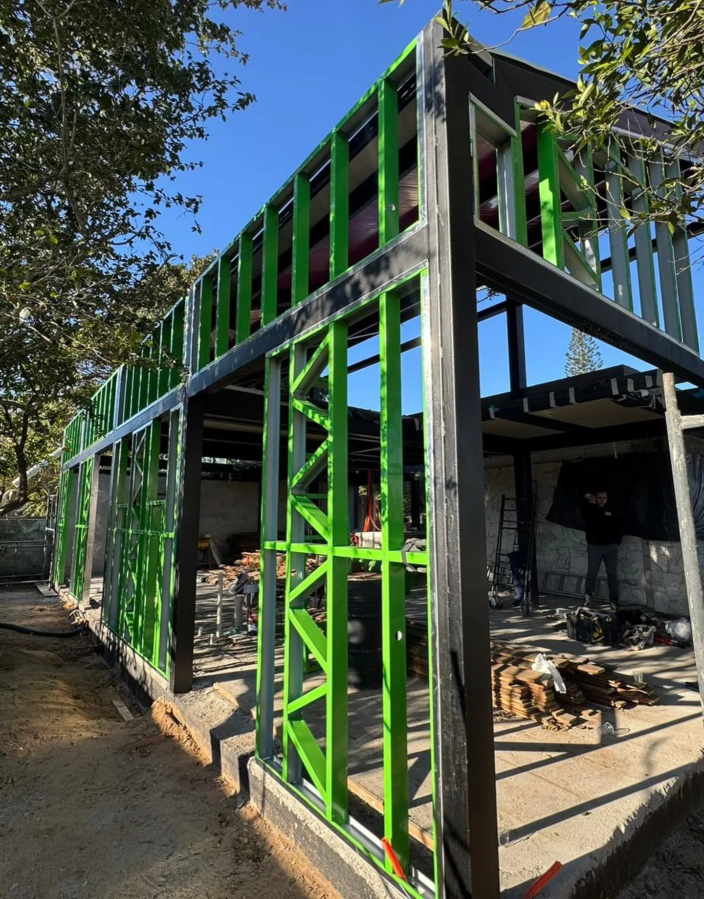 Painéis de parede em perfis de aço verdes montados em obra.